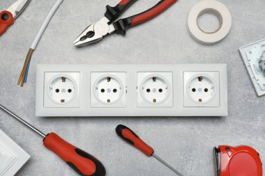 Elektrik prizi ve elektrikli aletler gri masada, düz yerde.