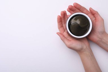Beyaz arka planda göz bandı olan kavanozu tutan kadın. Kozmetik ürünü