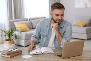 İçerideki masada internetten giysi izleyen genç adam.