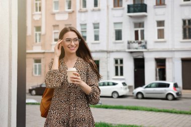 Elinde bir bardak içkiyle şehirde yürüyen genç bir kadın, mesaj için yer var.