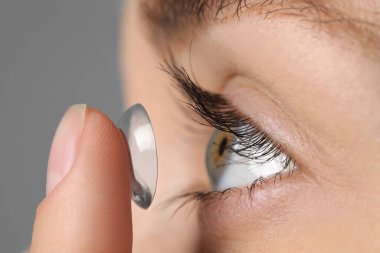 Gri arkaplana kontak lens takan kadın, yakın plan görünümü