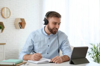 İçerideki masada internetteki web sitesinde notlar alan genç bir adam.