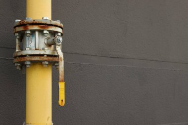 Açık havada kahverengi duvarın yanında vanası olan sarı gaz borusu, metin için boşluk