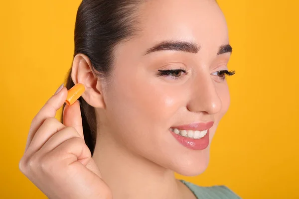 Młoda Kobieta Wkładająca Piankowe Zatyczki Uszu Żółtym Tle Zbliżenie — Zdjęcie stockowe