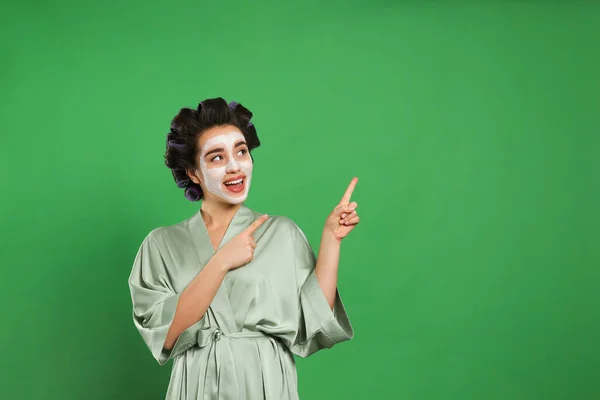 穿着丝绸浴衣的快乐年轻女人 头发卷曲 戴着绿色背景的面罩 有文字空间 — 图库照片