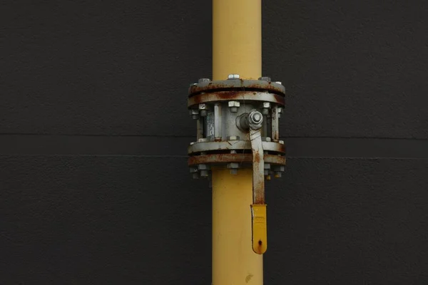 Yellow gas pipe with valve near brick wall outdoors