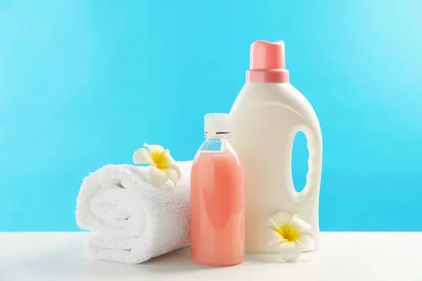Μπουκάλια Απορρυπαντικά Πλυντηρίων Πετσέτες Και Λουλούδια Plumeria Λευκό Τραπέζι — Φωτογραφία Αρχείου