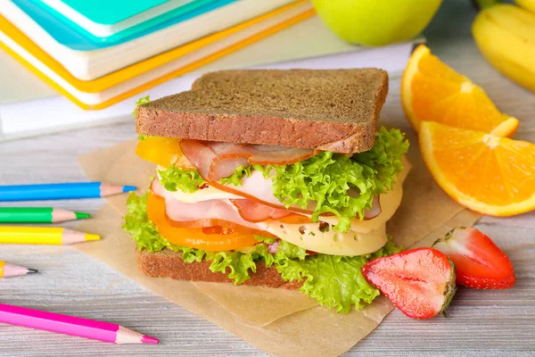 Tasty healthy food and different stationery on wooden table, closeup. School lunch