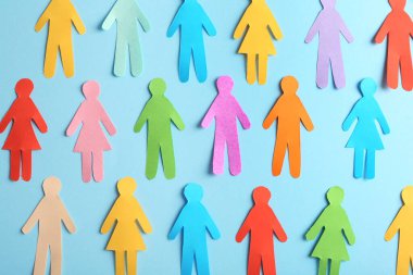 Many different paper human figures on light blue background, flat lay. Diversity and inclusion concept