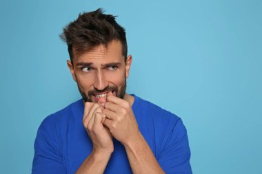 Adam açık mavi arka planda tırnaklarını yiyor. Metin için boşluk