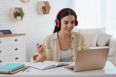 İçerideki masada internetten giysi izleyen genç bir kadın.