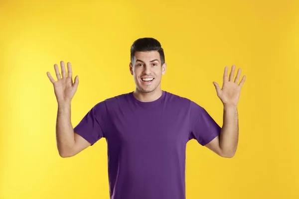 Cheerful man waving to say hello on yellow  background