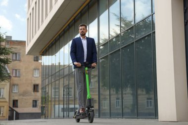 Şehir caddesinde modern scooter kullanan bir iş adamı.