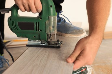 Yeni kaplama döşeme montajı sırasında yapboz kullanan profesyonel bir işçi.