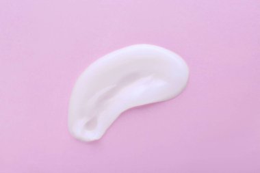 Pembe arka planda vücut kremi örneği, üst görünümde.