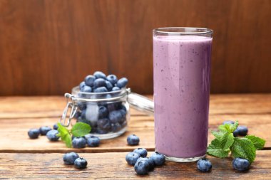 Bir bardak nane ve ahşap masada taze böğürtlenli yaban mersini püresi. Metin için boşluk