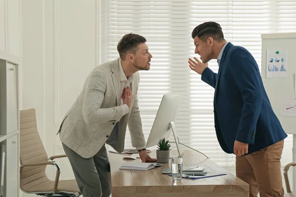 Colleagues fighting at table in office. Workplace conflict