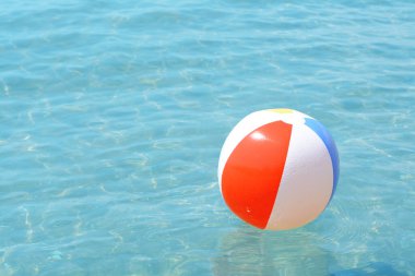 Güneşli bir günde denizde yüzen renkli plaj topu, metin için yer