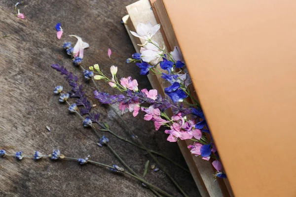 Beautiful dried flowers and books on wooden table, closeup