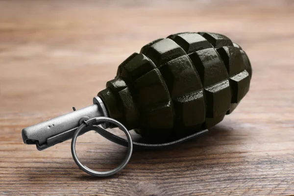 Hand grenade on wooden table, closeup. Explosive weapon