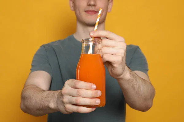 オレンジの背景にジュースのガラスを持つ若い男 クローズアップ — ストック写真