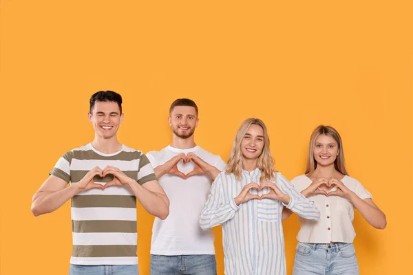 Gelukkige Vrijwilligers Die Harten Maken Met Hun Handen Oranje Achtergrond — Stockfoto