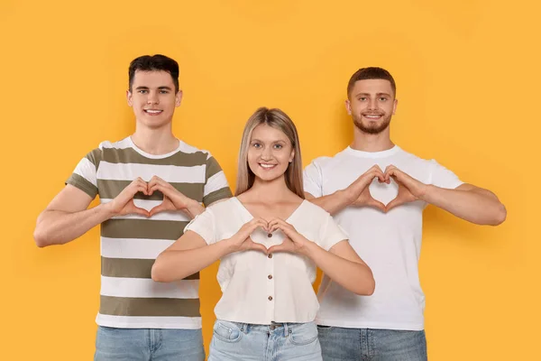 Gelukkige Vrijwilligers Die Harten Maken Met Hun Handen Oranje Achtergrond — Stockfoto