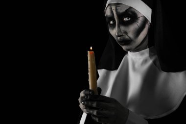 Siyah arka planda yanan mumu olan korkunç şeytani bir rahibe, mesaj için yer var. Cadılar Bayramı partisi görünüşü