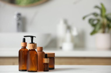 Banyodaki beyaz ahşap masada farklı kişisel bakım ürünleri. Metin için boşluk