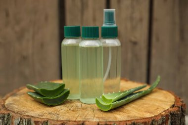 Kozmetik ürünleri şişeleri ve ağaç kütüğünde dilimlenmiş aloe vera yaprakları.