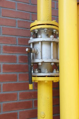 Kırmızı tuğla duvarın yanında sarı gaz borusu.