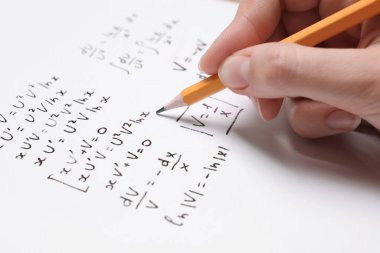 Kağıt üzerine farklı matematiksel formüller yazan öğrenci, yakın plan