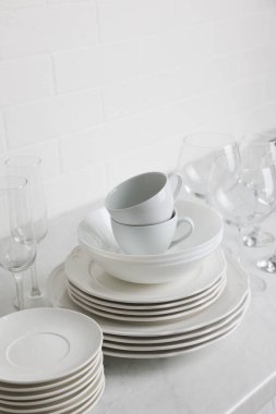 Tezgahta farklı temiz tabak, bardak ve bardaklar var.