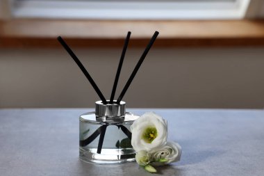 Reed diffuser and eustoma flowers on gray marble table