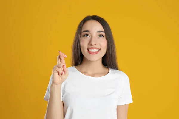 Podekscytowana Młoda Kobieta Trzymająca Kciuki Żółtym Tle Przesądy Szczęście — Zdjęcie stockowe