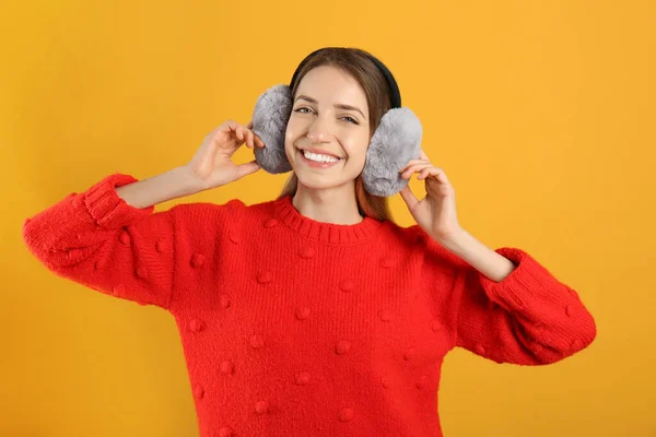 Sarı Arka Planda Sıcak Kulaklık Takan Mutlu Kadın — Stok fotoğraf