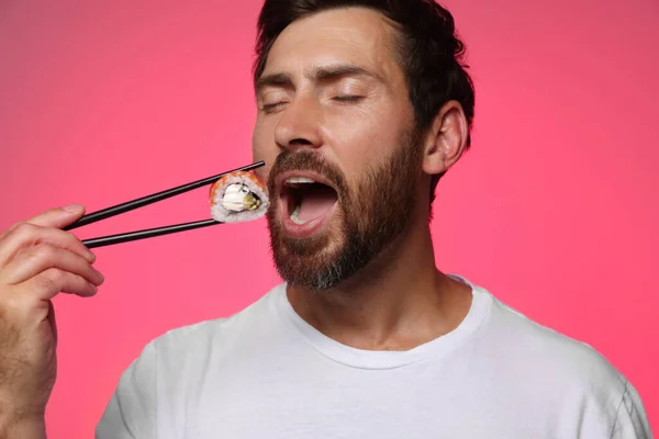 Handsome Man Eating Tasty Sushi Roll Chopsticks Pink Background — Stock Photo, Image
