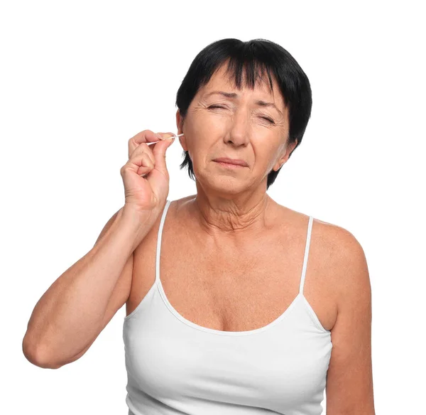 老年妇女用白色背景的棉签擦拭耳朵 — 图库照片