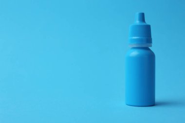 Açık mavi arka planda bir şişe tıbbi damla. Metin için boşluk