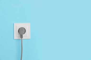 Açık mavi duvara yerleştirilmiş prizi olan güç soketi, metin için boşluk. Elektrik arzı