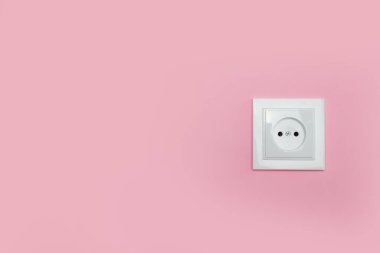 Power socket on pink wall, space for text. Electrical supply