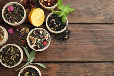 Tahta masadaki kaselerde farklı türde kuru bitkisel çay, düz yatak. Metin için boşluk