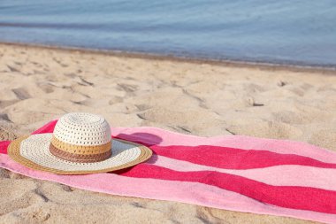 Plaj havlusu ve hasır şapka deniz kenarında kumda
