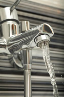 Water flowing from bath tap installed on black and white wall