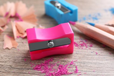 Keskinleştiriciler, renkli kalemler ve ahşap masa talaşı, yakın plan.