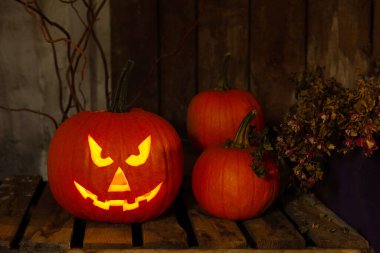 Karanlıktaki ahşap bankta duran korkunç balkabağı Jack O 'Lantern. Cadılar Bayramı Dekorasyonu