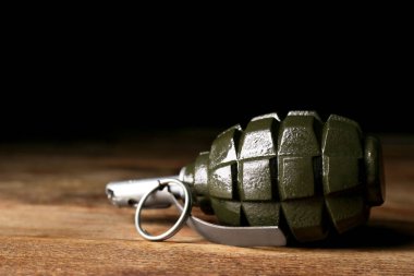 Ahşap masanın üzerindeki el bombası siyah arka plana karşı, yakın plan. Metin için boşluk