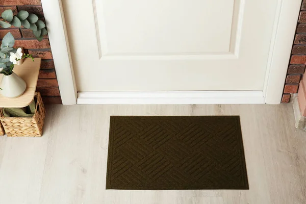 Dark olive door mat on wooden floor in hall, above view