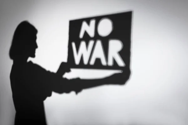 一个女人拿着写着 没有战争 的海报的影子 — 图库照片