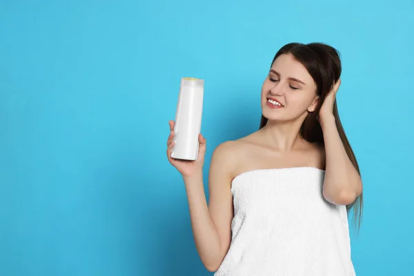 Schöne Junge Frau Handtuch Gewickelt Hält Flasche Shampoo Auf Hellblauem — Stockfoto